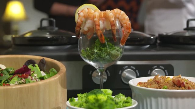 Shrimp Cocktail Move Right. camera moves right and spins keeping focus on shrimp cocktail display on a table surrounded by a variety of food dishes
