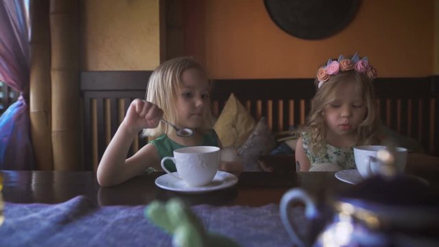 Two cute little girls are having tea in a cozy cafe