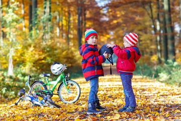 Two little kid boys with bicycles in autumn park