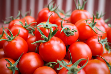 Cherry tomato in basket on wooden background.
