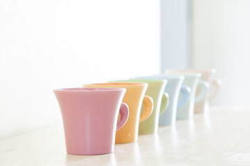 Row of colorful coffee cups on clear background.