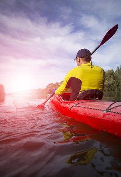 A man paddles a red kayak.