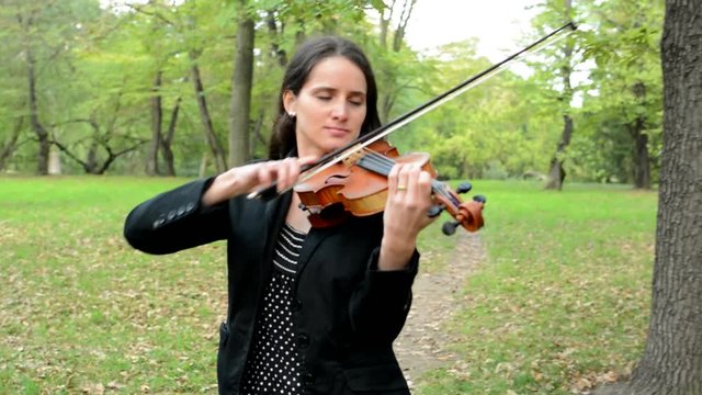 young happy attractive woman walk in the park and play on the violin - look around herself