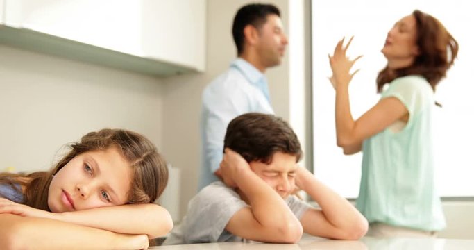Upset siblings covering their ears while their parents fight