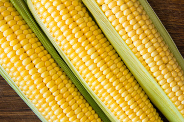 Ripe corn grains on cob and green leaves. Closeup