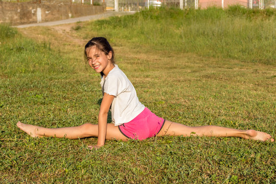 Юная девочка занимается гимнастикой, йогой на траве. Здоровый образ жизни.