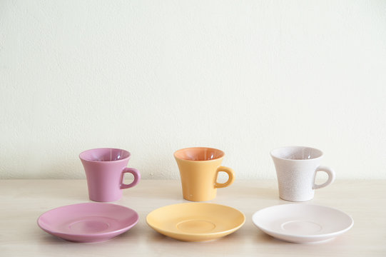 Pile of colorful modern cups of coffee on wooden table with the coffee dishes for prepare serve.