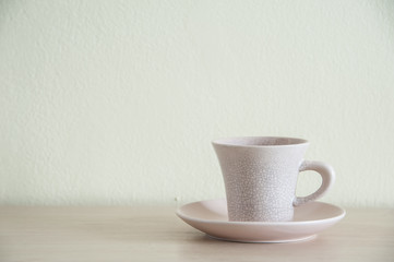 A cream coffee cup for take a break on the wooden table. Right space of frame.