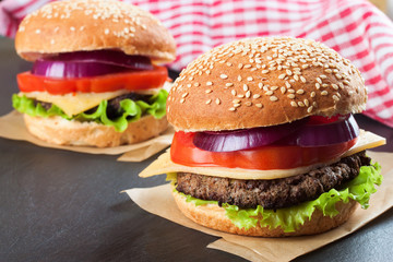Homemade cheeseburger on black slate surface.
