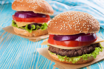 Homemade cheeseburger on blue wooden surface.