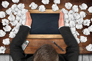 businessman clearing desktop with empty blackboard from paper snarl  /  Geschäftsmann befreit...