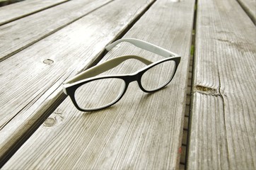 reading glasses in a plastic frame gray lie on wooden, natural table