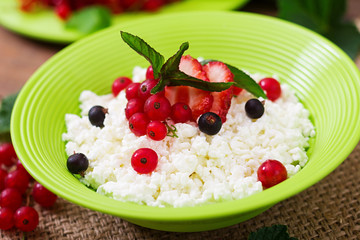 Cottage cheese for breakfast in green bowl on wooden background. Close up