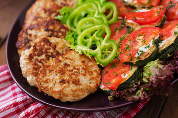 Dish with a snack of fried zucchini with tomatoes and succulent chicken cutlets with zucchini.