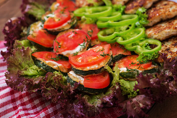 Dish with a snack of fried zucchini with tomatoes and succulent chicken cutlets with zucchini.