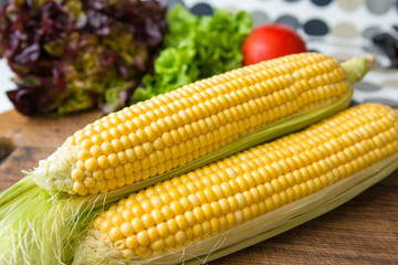 Ripe yellow corn cob on brown wooden board