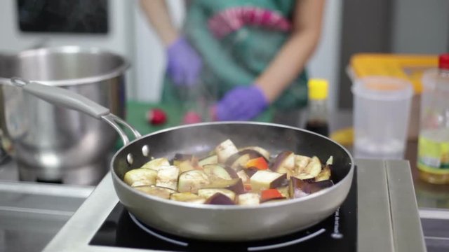 Eggplant ragout is being prepared in the pan on an electrick stove, fastfood kitchen background