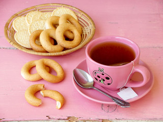 cup of tea, bagels and cookies on a pink background