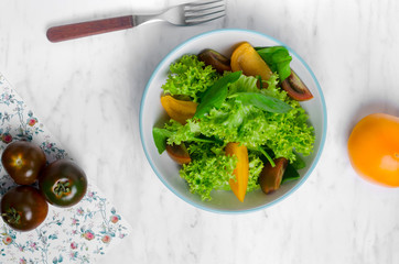 Healthy vegetarian salad with tomatoes in a bowl on a marble table