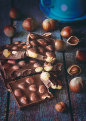Stack of dark black chocolate milk with hazelnut kernels on a wooden background, Toned Image