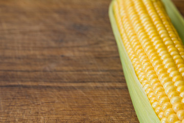 Ripe yellow corn cob on brown wooden board