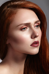 Beautiful ginger young woman with luxury hair style and fashion gloss makeup. Beauty portrait of sexy model with red hair. Long soft shiny hairstyle. Close-up studio shot of look redhead girl