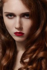 Fototapeta premium Beautiful young woman with clean skin, shiny red hair, fashion makeup. Glamour make-up, perfect blood lips. Portrait sexy ginger woman with curly hairstyle