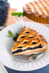 Serving of blueberry pie tart dessert served next to fresh organic ingredients on table