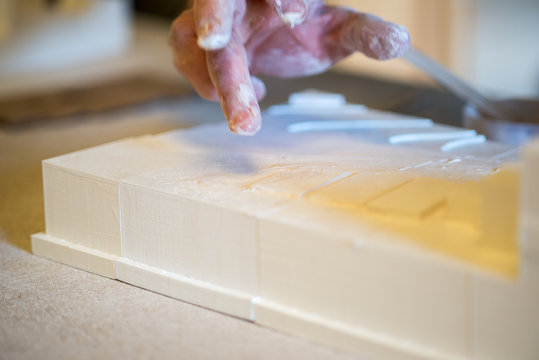 Fingers Dabbing White Paint on Plaster Building Model
