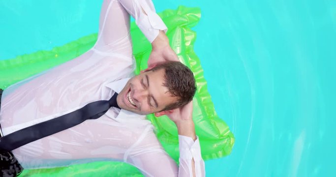 Businessman lying on lilo in swimming pool