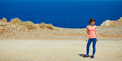 Happy woman enjoying freedom on travel in Crete coast, Greece. Female on summer or spring leisure vacation towards the sea