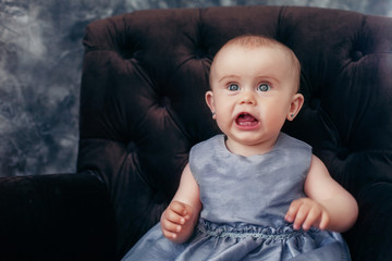 Fototapeta premium beautiful little baby with blue eyes in gray dress 