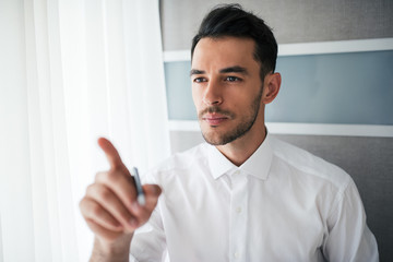 Portrait of attentive handsome businessman showing or pointing with a finger in the office. Business