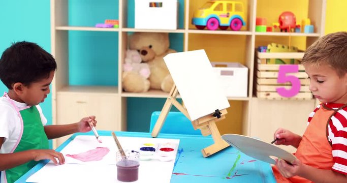 Cute little boys painting at table in classroom
