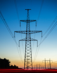 Fototapeta premium High voltage power lines with electricity pylons at twilight