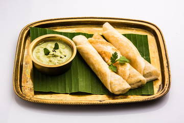 3 dosa rolls with coconut chutney in a brass tray over coconut leaf, favourite south indian meal