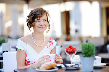 Young bride having breakfast and drinking coffee at the outdoors