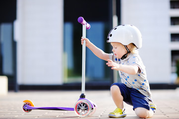 Toddler boy learning to ride scooter © Maria Sbytova