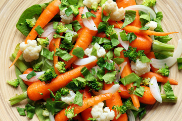 Fresh salad with baby carrots on wooden plate, top view