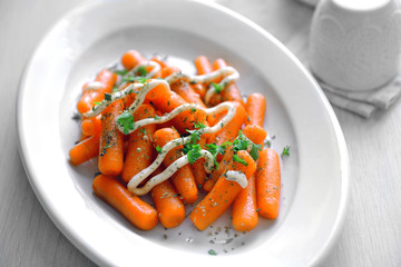 Baby carrot with greens and mayonnaise on plate closeup