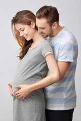 Fototapeta premium Happy family expecting baby on light background