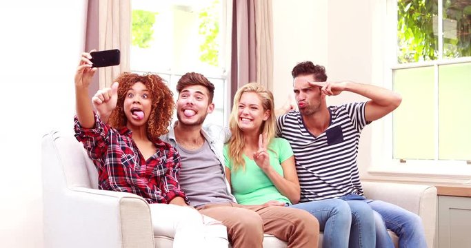 Happy friends taking selfie on the sofa