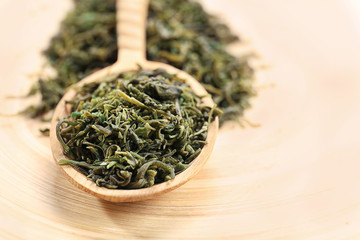 Fototapeta na wymiar Dry tea leaves in wooden spoon on table