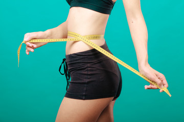 Fitness girl measuring her waistline
