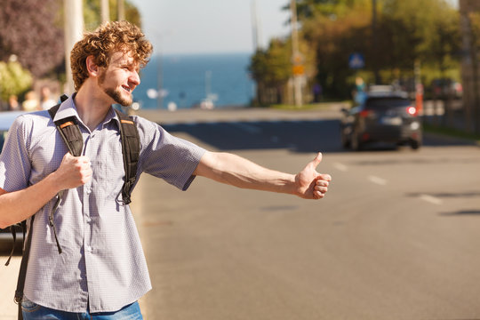 Happy man hitchhiking on summer vacation.