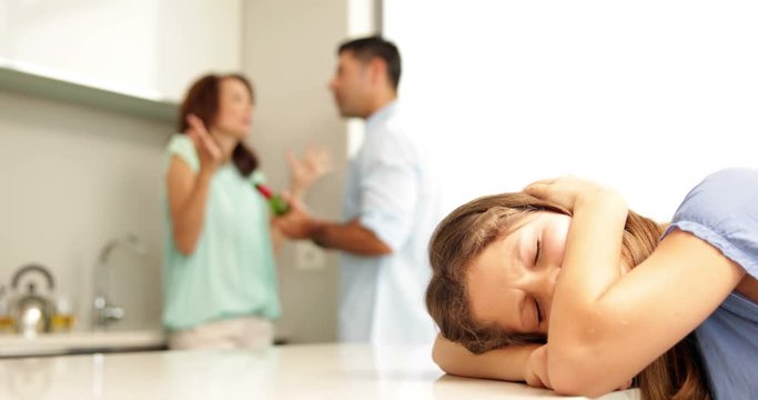 Upset girl covering her ears while her parents fight