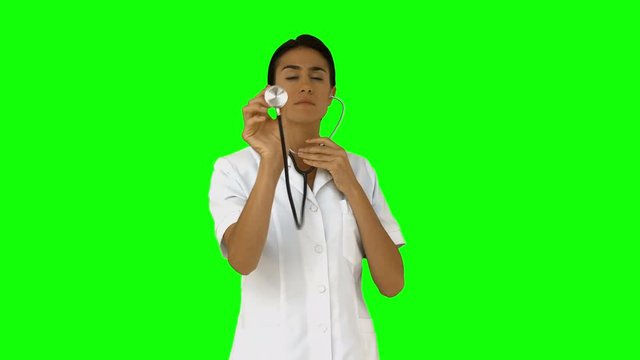 Nurse listening with her stethoscope on green screen background