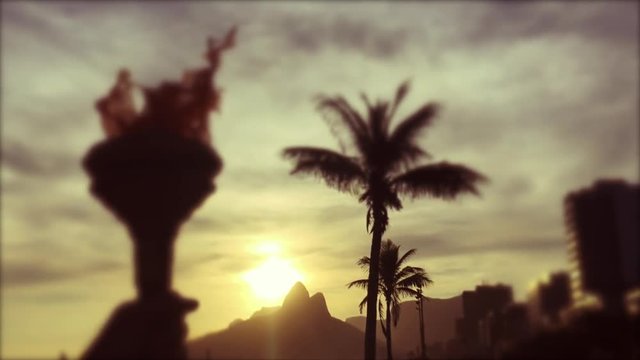 Silhouette of torchbearer athlete hand holding sport torch in selective focus at the Rio de Janeiro, Brazil sunset skyline at Ipanema Beach