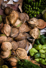Bali Market Goods. The local morning markets in Bali feature a varied mix of vegetables, fruit and meat. Women often arrive before daylight. Here are coconuts and mixed fruits.