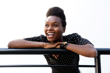 Young african woman leaning on railing and laughing